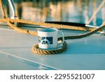 White cup with drawn helm on deck of a white yacht, ship, boat. Concept of tea coffee drinking while traveling at sea ocean. A mug in morning sunlight. Nautical wallpaper. Travel around the world.