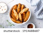 baked potato wedges with sauce on a light background, top view