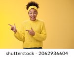 Small photo of Enthusiastic young millennial black girl cannot believe promo real widen eyes smiling surprised winning incredible chance lottery ticket pointing left index fingers telling you cool opportunity