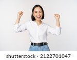 Small photo of Enthusiastic asian woman rejoicing, say yes, looking happy and celebrating victory, champion dance, fist pump gesture, standing over white background