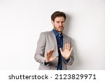 Small photo of Stay away. Reluctant businessman step back with concerned disgusted face, raising hands to block bad offer, rejecting something awful, tilting from disgust, white background