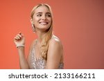 Small photo of Elegant glamour gorgeous young rich blond woman attend charity party in stylish silver glittering dress accessorize turning right smiling greeting familiar person grinning joyfully, red background