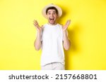 Small photo of Concept of tourism and summer. Happy young man in straw hat looking amazed, reacting to surprise, standing over yellow background