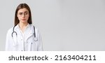 Small photo of Healthcare workers, medicine, insurance and covid-19 pandemic concept. Skeptical and confused female doctor in white scrubs, medical suit and glasses, raise eyebrow judgemental, smirk displeased
