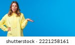 Small photo of Whats wrong, why. Confused and frustrated blond girl dealing with person complains, shrugging and raise one hand in dismay grimacing perplexed, look camera questioned, blue background.