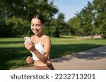 Small photo of Happy asian fitness girl running and checking her stats, daily goals on smartphone app. Young woman jogging and looking at mobile screen.