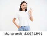 Small photo of Portrait of confident woman, showing okay, ok sign in approval, nod and say yes, recommend smth, standing over white background.