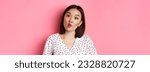 Small photo of Beauty and lifestyle concept. Close-up of funny and cute asian woman pucker lips, showing fish mouth and standing playful, standing over pink background.
