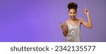 Small photo of Sassy good-looking african-american woman in trendy glamour silver shiny dress index fingers raised up smiling cheeky joyfully celebrating great lucky news dancing grinning, standing blue background.