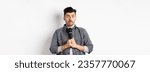 Small photo of Nervous unconfident guy holding microphone and look indecisive, scared to perform, standing shy against white background.