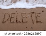 Small photo of Write the letters D E L E T E on the sand and there is sea water coming to erase the letters. Used to communicate the erasure disappears from the memory. or delete it or restart, message delete.