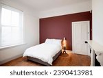 Small photo of Interior of modern bedroom with double bed and white linen, color ful wall with patterns. Accent wall with maroon and blue diagonal wall paint.