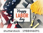 Small photo of HAPPY LABOR DAY. Text in notebook HAPPY LABOR DAY with hammer, ax, monkey wrenches and flag of America on gray background. The concept of the holiday, labor day. Flat lay.