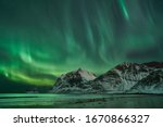 Hauklandbeach, Lofoten / Norway - March 7th 2019: huge northern lights / aurora outbreak over fjord at hauklandbeach near Leknes. lights dazzled green, white over mountains of fjord Vikbukta