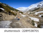 Small photo of mother and son walking in the snowy mountain next to a river and snowfields. precocious mountain in the pyrenees