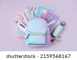 Opened School backpack with stationery in pastel color on pink background. Concept back to school. School supplies.