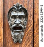 Small photo of brass door knocker in the shape of a monstrous human face. High quality photo
