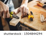 A man carves a tree. The carpenter works with pliers in a studio. An engineer provides a tree shape