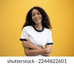 Small photo of International Woman day power African American woman huge embraces equity herself, feels good, fulfilled, has high self esteem, tilts head and smiling wears white shirt isolated on yellow background.