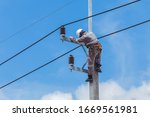 Electricians Wiring Cable repair services,worker in crane truck bucket fixes high voltage power transmission line,setting up the power line wire on electric power pole,Soft focus,selective focus.