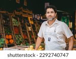 Middle-aged Latin man in an apron looking at the camera in the greengrocer's shop where he works. Copy space.
