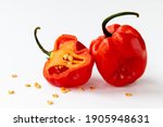 Isolated image of a whole and half of a habanero red chilli pepper with seeds around on a white background.