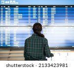 Back view of a woman looking at the airport schedule