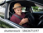 Young asian man using smartphone while driving car.