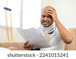 Small photo of UnHappy man stressed pay invoice medical expenses from accident fracture broken bone injury with leg splints in cast neck splints collar sling support arm. Social security and health insurance.