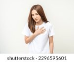 Small photo of Asian woman around 25 year She felt a pain in her chest held her hand and squeezed it. She had a heart attack that needed treatment. Wearing white shirt standing on isolated background.