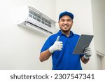 Small photo of Technician in uniform using tablet to check list of maintenance and cleaning filters of air conditioner. Air condition maintenance service. Home services concept.