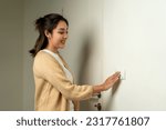 Small photo of Earth Hour. Asian beautiful woman turn off or on the light to saving electrical energy. Finger pushing light switch turn on or off. White switch