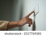 Small photo of Earth Hour Close up woman finger turn off or on the light to saving electrical energy. Finger pushing light switch turn on or off. White switch