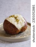 Small photo of Close-up of one fresh pistachio Maritozzo on a plate, an italian roman breakfast sweet, whipped cream sandwiched between brioche