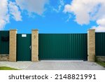 Small photo of Green metal profile fence with block posts. Entry group: gate, wicket and postbox. Opaque surface, vertical lines. Security. Private property fencing. Exterior. Pavement tiles on parking. Isolated.