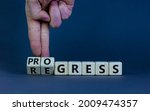 Small photo of Regress or progress symbol. Businessman turns wooden cubes and changes the word 'regress' to 'progress'. Beautiful grey table, grey background, copy space. Business, regress or progress concept.