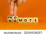 Small photo of Promote or demote symbol. Businessman turns cubes and changes the word 'demote' to 'promote'. Beautiful orange background. Business, demote or promote concept. Copy space.