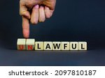 Small photo of Lawful or unlawful symbol. Businessman turns wooden cubes and changes the word unlawful to lawful. Beautiful grey table, grey background, copy space. Business and lawful or unlawful concept.