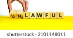 Small photo of Lawful or unlawful symbol. Businessman turns wooden cubes and changes the word unlawful to lawful. Beautiful yellow table, white background, copy space. Business and lawful or unlawful concept.