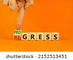 Small photo of Regress or progress symbol. Businessman turns wooden cubes and changes the word Regress to Progress. Beautiful orange table orange background. Business regress or progress concept. Copy space.