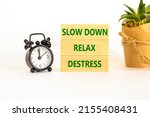 Destress symbol. Concept words Slow down Relax Destress on wooden block. Black alarm clock. Beautiful white table white background. Psychological business slow down Relax destress concept. Copy space.