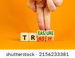 Small photo of Trash to treasure symbol. Businessman turns cubes and changes the word trash to treasure. Beautiful orange table, orange background. Business, trash to treasure concept. Copy space.