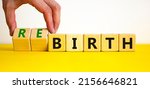 Small photo of Birth or rebirth symbol. Businessman turns wooden cubes and changes the word birth to rebirth. Beautiful yellow table white background, copy space. Business, birth or rebirth concept.