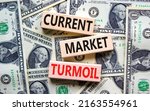 Small photo of Current market turmoil symbol. Concept words Current market turmoil on wooden blocks on a beautiful background from dollar bills. Business, finacial current market turmoil concept. Copy space.