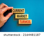 Small photo of Current market turmoil symbol. Concept words Current market turmoil on wooden blocks on a beautiful blue table blue background. Businessman hand. Business, finacial current market turmoil concept.