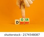 Small photo of Doer or dreamer symbol. Concept words Doer or dreamer on wooden cubes. Businessman hand. Beautiful orange table orange background. Business and doer or dreamer concept. Copy space.