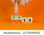 Small photo of Doer or thinker symbol. Concept words Doer or thinker on wooden cubes. Businessman hand. Beautiful orange table orange background. Business and doer or thinker concept. Copy space.