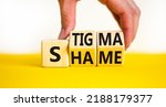 Small photo of Stigma or shame symbol. Concept words Stigma or Shame on wooden cubes. Businessman hand. Beautiful yellow table white background. Business stigma or shame concept. Copy space.