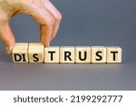 Small photo of Distrust or trust symbol. Businessman turns wooden cubes, changes words 'distrust' to 'trust'. Beautiful grey table, grey background. Business and distrust or trust concept, copy space.