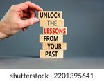Small photo of Lessons from your past symbol. Concept words Unlock the lessons from your past on wooden blocks. Bussinesman hand. Beautiful grey background. Business and lessons from your past concept. Copy space.